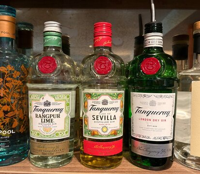 A selection of Tanqueray gin flavours on a wooden shelf in a cosy British Scottish pub setting, original, Sevilla orange and Rangpur lime