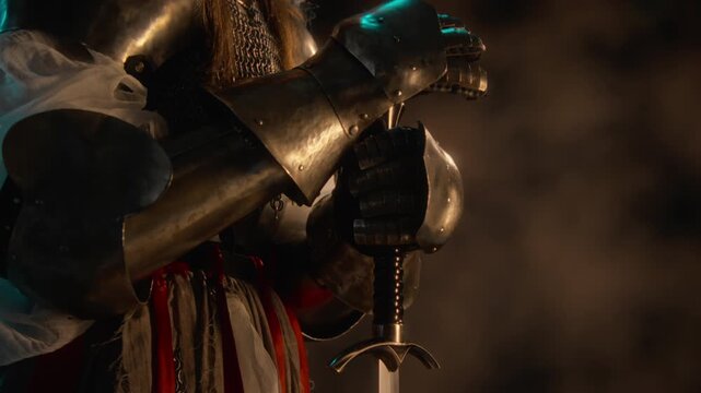 Unknown knight in steel armor resting armored hands on sword hilt. Footage suited for historical documentaries, fantasy video game marketing and cinematic storytelling