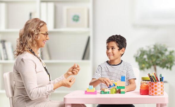 Woman talking to a child playing with building blocks