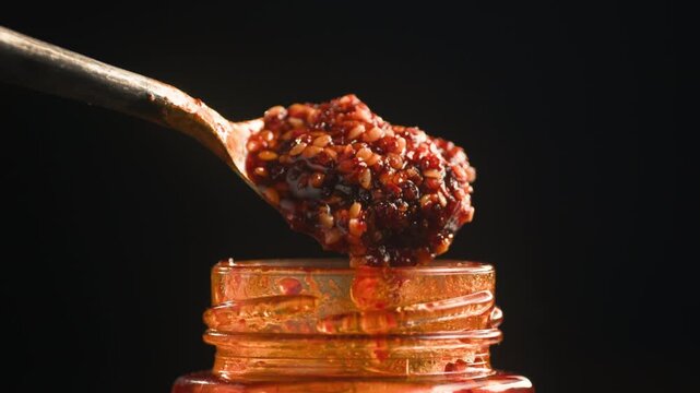 Chinese Crispy Chili Oil in Glass Jar, Homemade Chili Crisp with Garlic, Shallots and Sesame Seeds, Authentic Spicy Asian Condiment, Close Up Macro Video for Cafe and Restaurant Menu