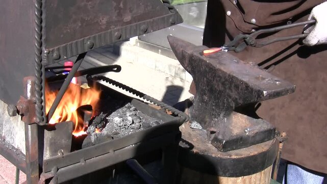 Blacksmith work close up, bending hot metal bar, two takes.