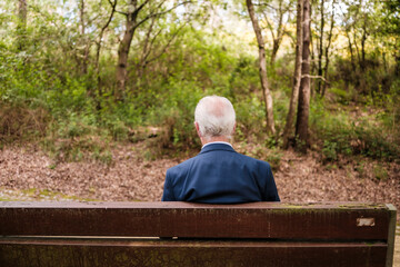 Fototapeta premium Elderly man reflecting on park bench in nature