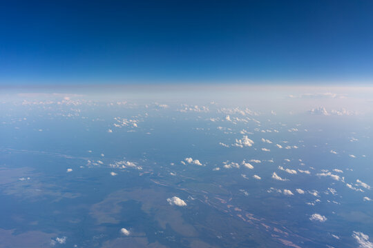 Minimal blue aerial horizon with scattered clouds and generous copy space