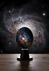 Fototapeta premium Cosmic exploration and space discovery, glowing nebula inside a crystal sphere on a wooden desk with deep space galaxy background for science research
