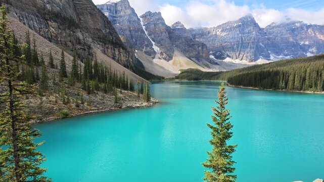 Moraine Lake's turquoise water reflecting in Banff National Park, surrounded by towering Canadian Rocky Mountains and evergreen forest, inviting tourism, outdoor summer in Alberta Canada. aerial view