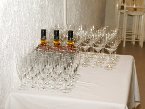 Verres &agrave; vin et fl&ucirc;tes dispos&eacute;s avec des bouteilles de spiritueux avant le service lors d&rsquo;une r&eacute;ception de mariage