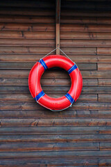 Red lifebuoy hanging on dark wooden wall background © Vivid Moments