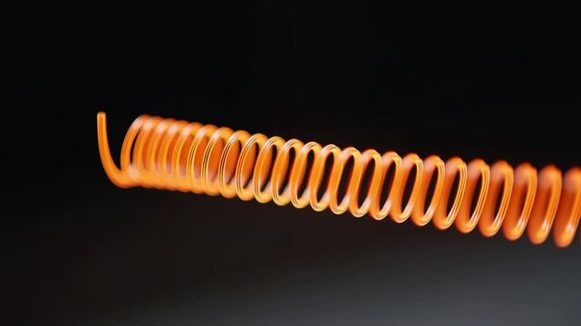 Metal coil spring resting horizontally against dark background in closeup detail