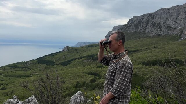 Mature Man Watching Mountains With Binoculars