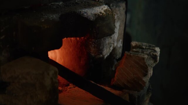 Blacksmith Heating Glowing Metal Bar in Forge Fire