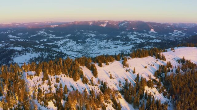 An extraordinary valley with hills and mountains covered with fir forests against the backdrop of a bright pink sunset