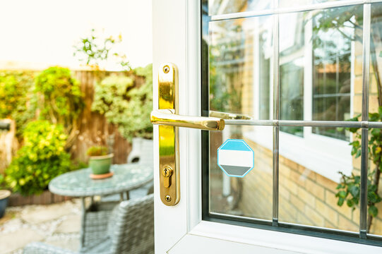 Shallow focus of a newly fitted double glazed and leased window kitchen door with brass lock and door handle. Leading to a patio area in a rear garden.
