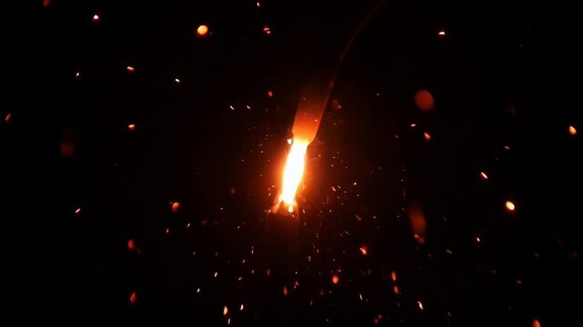 ?Sparkler ignites with bright sparks and glowing trails in dark background
