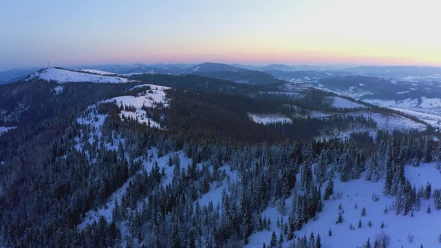 An extraordinary valley with hills and mountains covered with fir forests against the backdrop of a bright pink sunset