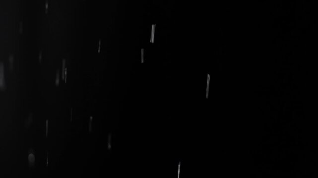 Wet snow and streams of water flow onto the black isolated background of the studio in dim lighting, an empty template for advertising objects.