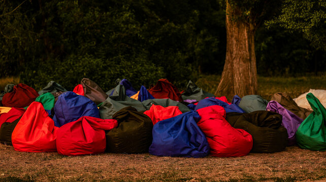 A large pile of colorful bean bag chairs scattered on the ground outdoors