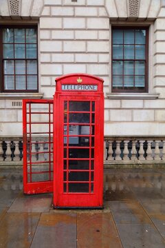 London red telephone in rainy weather. English symbol - red phone booth street view in Westminster.