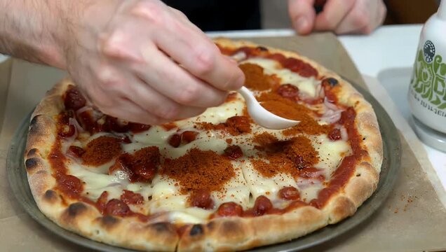 Appetizing 4K pizzeria close-up capturing a shower of bright red crushed pepper flakes landing on a fresh slice of thick-crust Detroit-style pepperoni pizza highlighting savory cheese textures