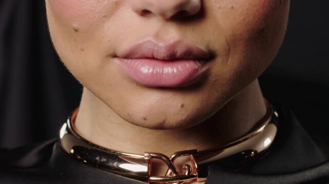 Responding to cue, model forming syllables in studio, wearing gold choker and satin top