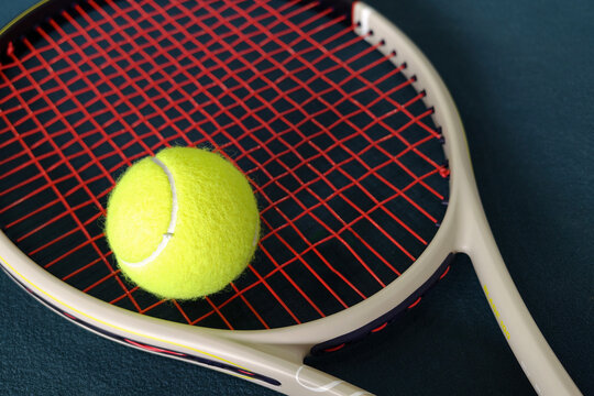 Tennis racket and yellow ball on court surface
