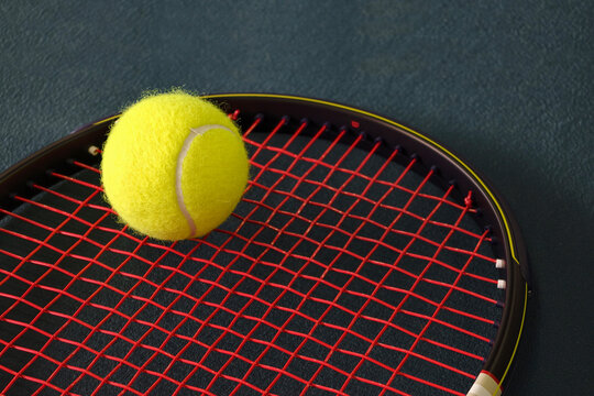 Tennis racket and yellow ball on court surface