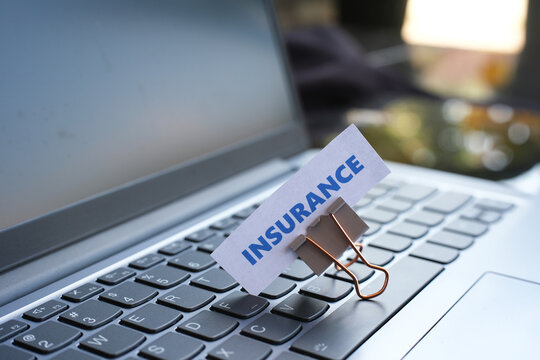 The word "INSURANCE" written on a piece of paper placed on top of a laptop keyboard.