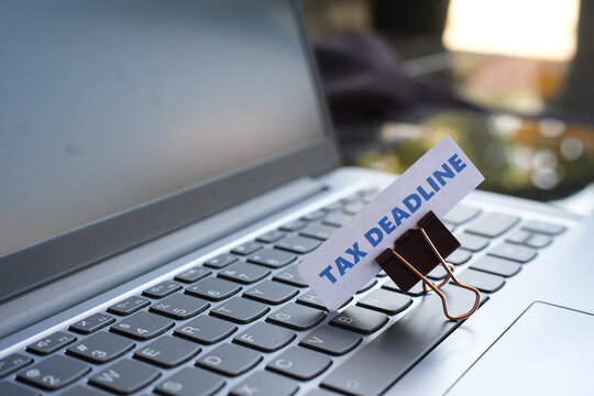 A note reading "TAX DEADLINE" is clipped to the top of a keyboard, serving as a reminder that the tax payment deadline is approaching.