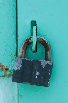 An old metal lock on a green metal door.