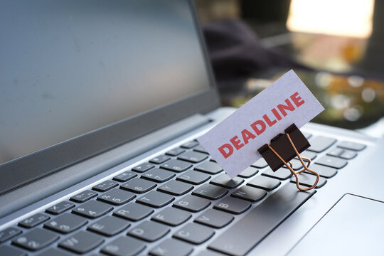 Deadline &ndash; the date or time by which something must be completed; the word "DEADLINE" attached with a paperclip to a laptop keyboard. Racing against time; under pressure.