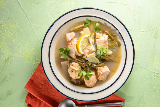 Sinigang na Baboy salmon Soup in gray bowl on concrete backdrop. Sinigang is a Filipino cuisine dish with meat, taro root, daikon, green bean, eggplant, fish sauce. Filipino Food. Asian Meal. Top view