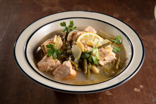 Sinigang na Baboy salmon Soup in gray bowl on concrete backdrop. Sinigang is a Filipino cuisine dish with meat, taro root, daikon, green bean, eggplant, fish sauce. Filipino Food. Asian Meal. Top view