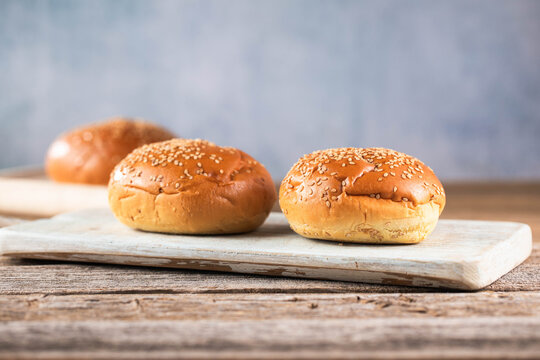 Empty burger bun with sesame seeds on a kitchen table.