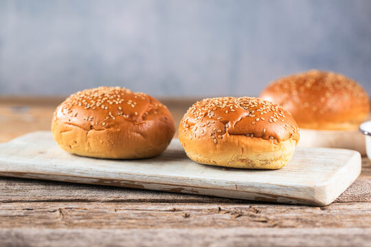 Empty burger bun with sesame seeds on a kitchen table.