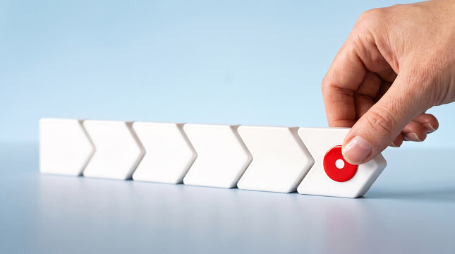 Hand pressing red start button on white arrow blocks