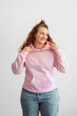 Pink hoodie fabric quality shown by model holding hood, soft fleece texture of blank hoodie for apparel brand, hoodie material detail for clothing production. Waist up. Concept of fabric quality © iwavephoto