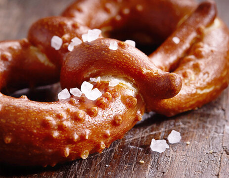 Macro shot of a fresh soft pretzel with coarse sea salt on wooden table