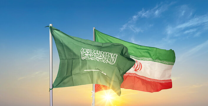 Saudi Arabia and Iran Flags Waving Together Against Sunset Sky