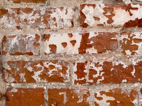Damaged old red brick wall texture background. Ancient brickwork surface with peeling white plaster and cracked stones for rustic grunge loft interior architecture design concept.