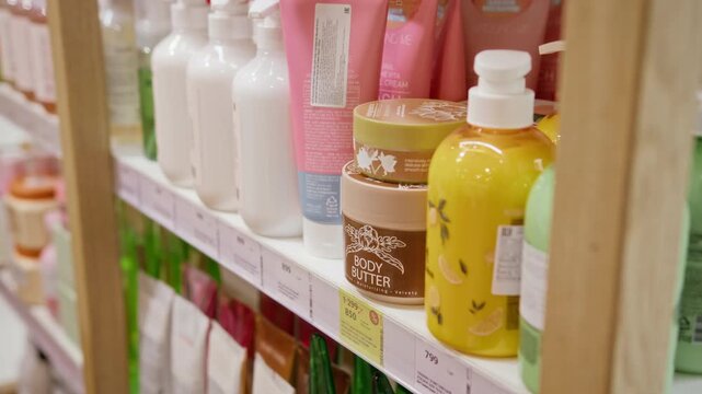 Row of cosmetic skincare products and body butter jars sitting on wooden shelf in beauty store. Footage fits beauty marketing campaigns, retail promotions, and skincare commercials