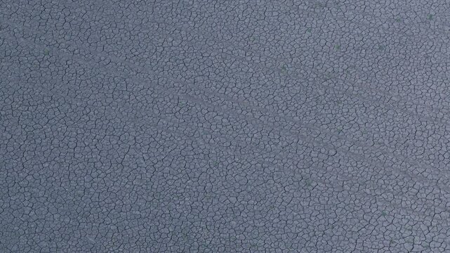 Aerial drone view of Arid cracked earth reflecting drought and desertification with small green sprouts appearing