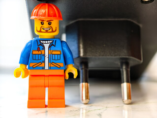 Fototapeta premium Russia, St. Petersburg, August 8, 2020 A small Lego man standing next to an electrical outlet