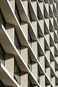 Geometric concrete facade with repeating balconies and deep shadows creating an abstract architectural pattern across a modern building exterior
