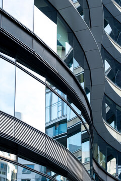 Curved modern building facade with glass windows and sweeping architectural lines creating abstract geometry in a contemporary urban composition