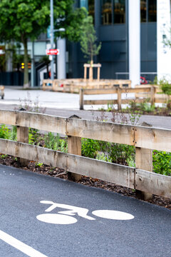 Urban bicycle lane with white cycling symbol beside roadside barrier and greenery showing city mobility infrastructure in an everyday transport setting