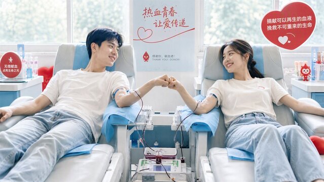 Young Couple Donating Blood Together: A young couple holds hands while donating blood, sitting in comfortable chairs at a blood donation center, embodying a spirit of selfless contribution.