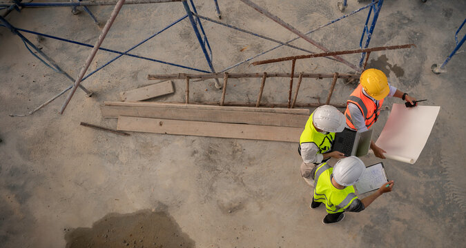 A team of engineers consults and plans the construction of the building. The architect, supervisor, and foreman meet to discuss the design of the building,working at site of a large building project