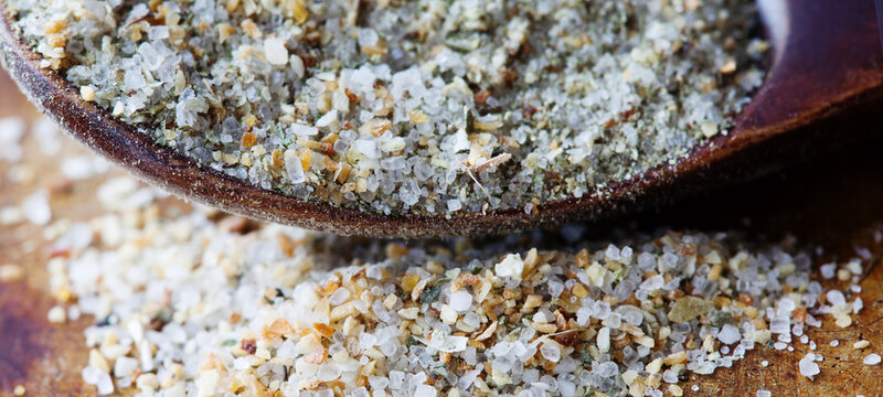 Garlic salt macro view. Mineral saline sodium chloride organic food condiment in wooden spoon, aged rusty background. Shallow depth field