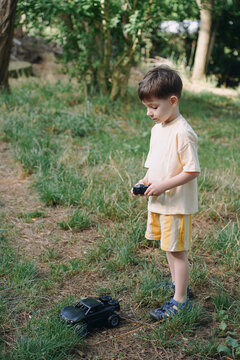 A Little Boy Spends Time Playing With A Car In The Fresh Air