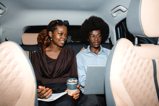 Two Black business professionals working together in the back seat of