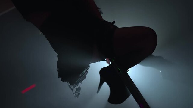 Pole dancer silhouette in backlit smoke on stage.